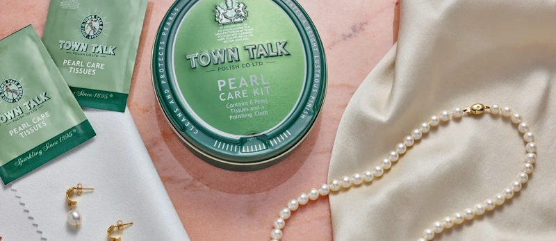 Delicate pearl necklace being gently wiped with soft cloth showing special care required for organic gemstones