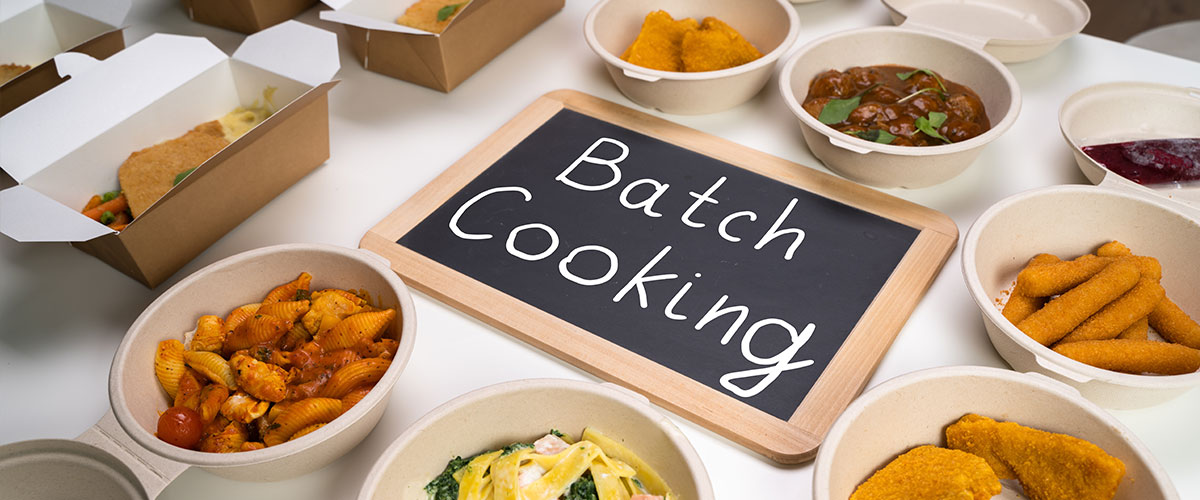 Sheet pans with roasted vegetables and proteins demonstrating batch cooking meal prep techniques