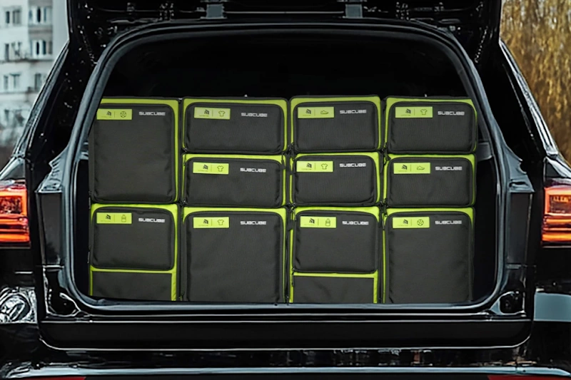 Well organized electric vehicle cargo area featuring modular trunk storage system with labeled compartments for charging equipment clothing emergency supplies and travel accessories demonstrating efficient space utilization for extended EV road trip organization InfoProds 2026