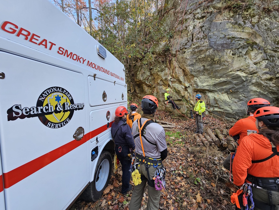 Professional search and rescue team members demonstrating evidence-based cold weather survival techniques and proper hypothermia prevention protocols during wilderness emergency response training exercise in rocky mountain terrain, showing contrast between survival myths and actual life-saving procedures - InfoProds 2026