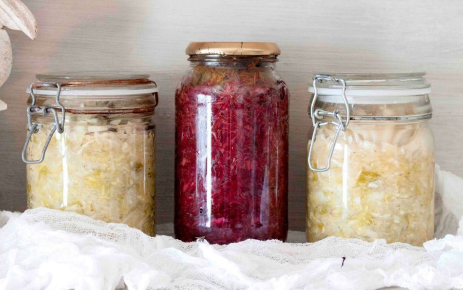 Fermentation crocks and glass jars containing sauerkraut kimchi and pickled vegetables demonstrating lacto-fermentation preservation method that creates shelf-stable probiotic-rich foods without refrigeration - InfoProds Healthy Kitchen 2026