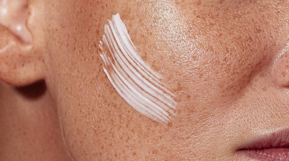 Young woman demonstrating proper moisturizer application technique by applying hydrating cream to damp facial skin immediately after gentle cleansing to lock in moisture and prevent transepidermal water loss - InfoProds 2026 skincare routine tutorial