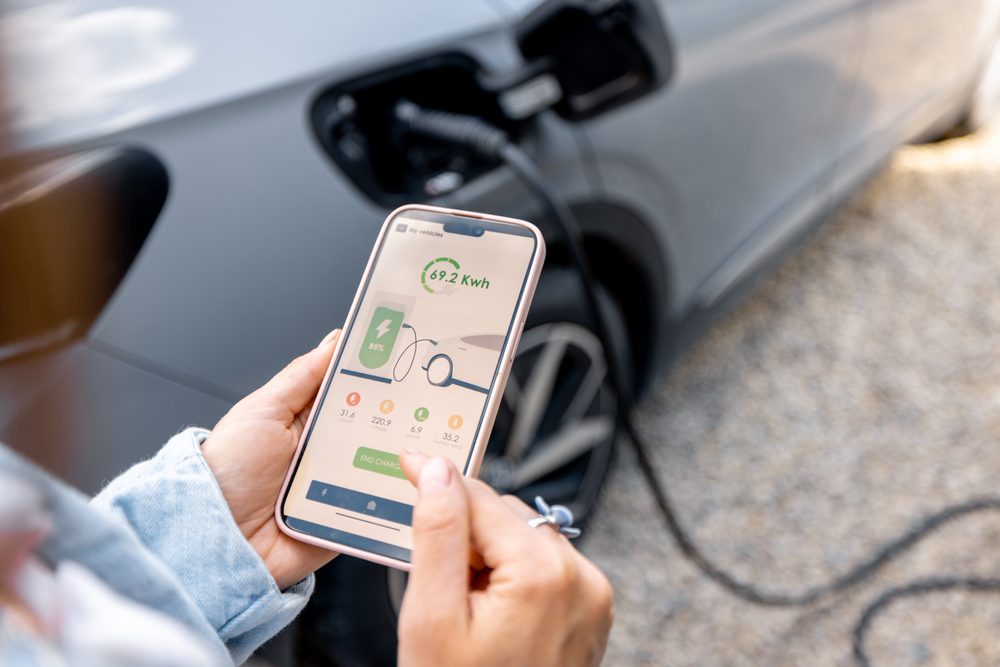 EV owner using mobile charging app to schedule off-peak charging optimize time-of-use electricity rates and manage total ownership costs - InfoProds 2026