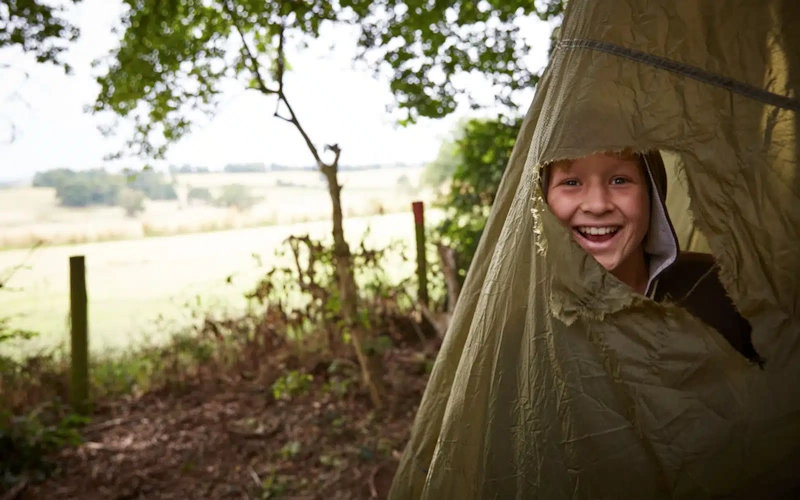 Emergency shelter built from tarp and natural materials during backyard survival skills weekend training showing practical construction techniques and weatherproofing methods - InfoProds 2026