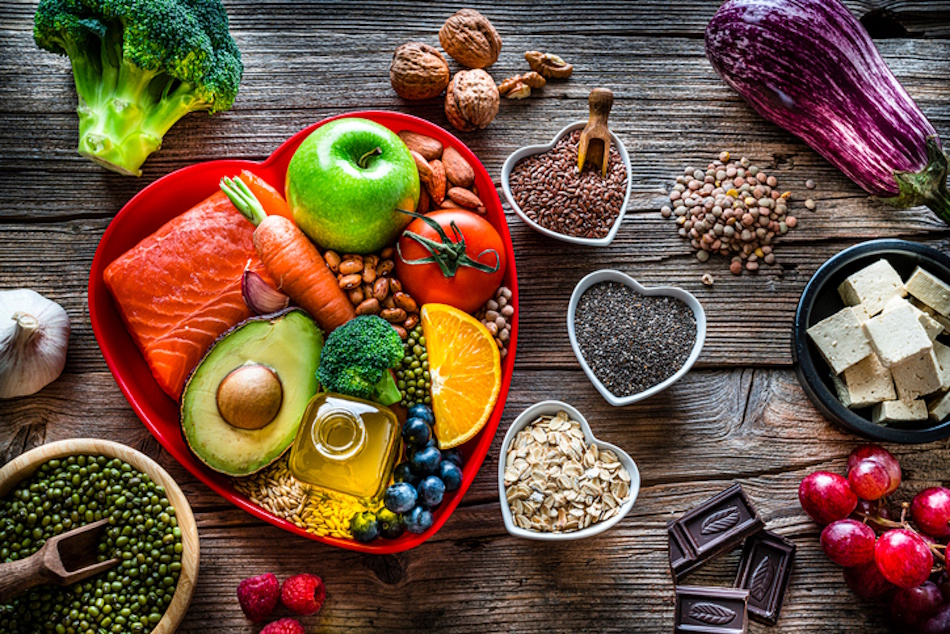 Vibrant collection of heart-healthy whole foods including fresh vegetables, colorful fruits, whole grains, nuts, seeds, fatty fish, and olive oil arranged to showcase nutrition for strengthening heart muscle and circulatory system health - InfoProds 2026