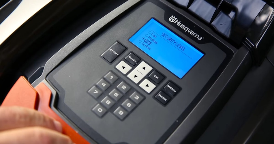 Close-up view of robotic lawn mower showing enclosed blade safety mechanism, lift sensors, PIN code security pad, GPS tracking module, automatic blade stop system, consumer safety compliance labels - InfoProds Mower Safety Standards 2026