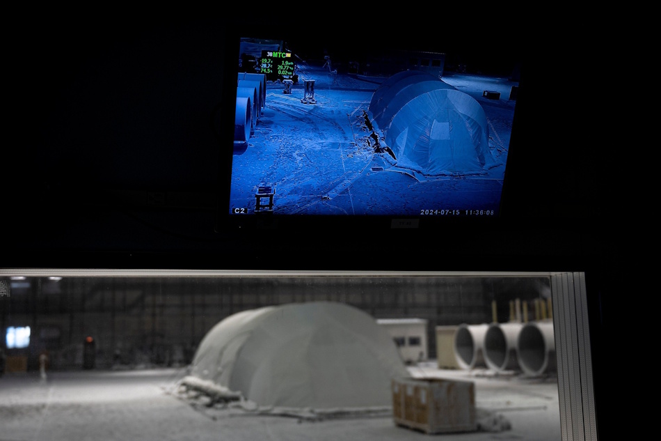 Nighttime emergency scenario testing showing volunteer setting up survival shelter using headlamp illumination during simulated rainstorm conditions demonstrating real-world deployment challenges and time constraints - InfoProds Survival Skills Training 2026