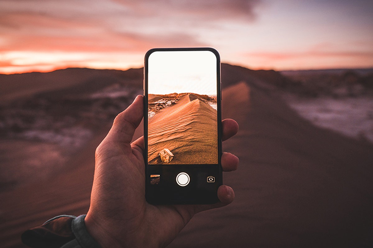 Content creator using smartphone for mobile photography workflow showing instant editing sharing and social media publishing capabilities that provide convenience advantages over dedicated camera systems - smartphone photography benefits InfoProds 2026