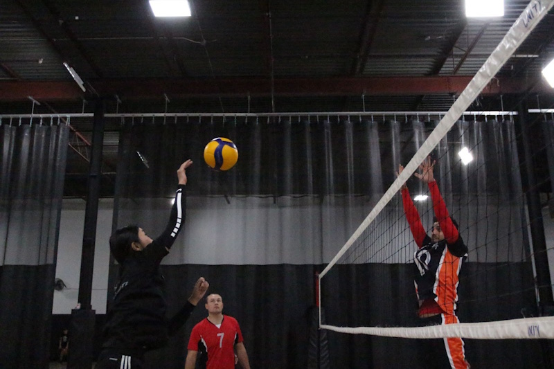 A wide shot of a volleyball team scrambling to their specialized positions immediately after the ball is served, showing the complexity of the specialization switch - InfoProds 2026