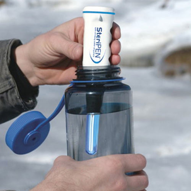 UV light water purifier in field conditions Portable UV water purifier device treating clear mountain stream water demonstrating ultraviolet disinfection technology effectiveness against waterborne pathogens in wilderness environment - InfoProds 2026