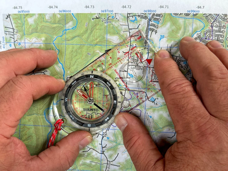 Wilderness navigation using map and compass for terrain reading and backcountry wayfinding demonstrating technical skills for forest mountain travel - InfoProds 2026